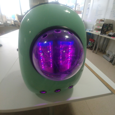 Turquoise hard shelled backpack with a clear bubbled window. Inside are 2 plastic containers holding micro-ecosystems lit by LEDs.
