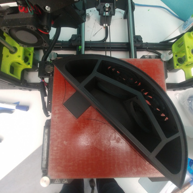 A completed 3D print of a section of a casing, sitting on a 3D printer bed.