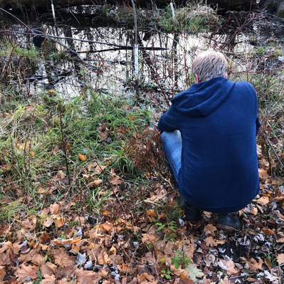 Man squatting by swamp