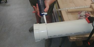 Work-in-progress of the prototype. Someone is sealing the threaded pipe-end onto the pipe with silicone.