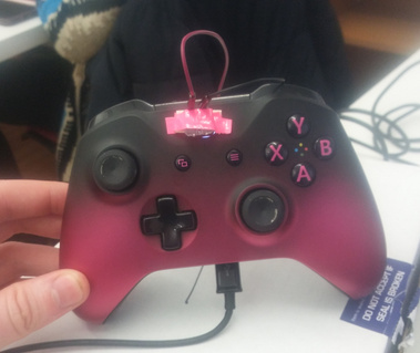 A black and pink controller, with a pink button wired over the power button.