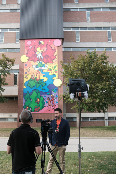 Ojibwe artist Mike Cywink is interviewed by CTV Kitchener in front of his mural, One Heart. One Mind. One Vision.