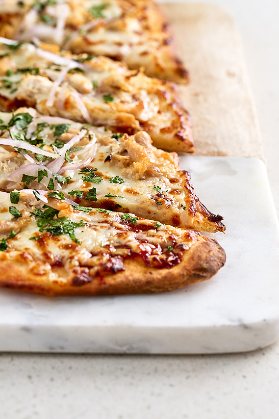 Macro three quarter shot of flat bread sliced on the diagonal and places atop a marble serving stone. Image by Megan Morello Commercial food photographer and lifestyle photographer in San Diego, Southern California.