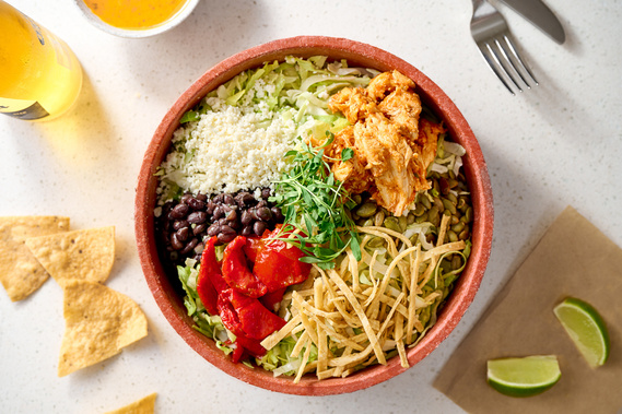 Overhead shot of a vibrant taco salad with ingredients in separate piles within bowl. Corona beer, chips, and lime also in frame.
Image by Megan Morello Commercial food photographer and lifestyle photographer in San Diego, Southern California.