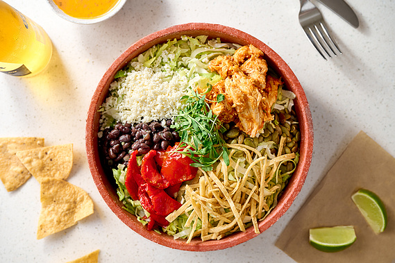 Overhead shot of a vibrant taco salad with ingredients in separate piles within bowl. Corona beer, chips, and lime also in frame.
Image by Megan Morello Commercial food photographer and lifestyle photographer in San Diego, Southern California.