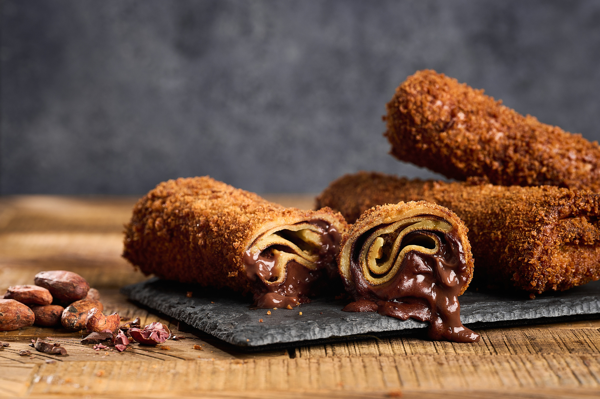 Deep fried chocolate filled crepes rolled like little burritos. One crepe is cut in half and chocolate is oozing out. Image by Megan Morello San Diego Food and lifestyle photographer.