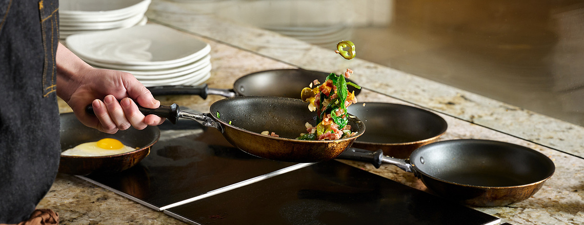 Close up of chef tossing vegetables in a pan. Cross-section of jalapeño pepper caught in mid-air. Image by Megan Morello Commercial food photographer and lifestyle photographer in San Diego, Southern California.