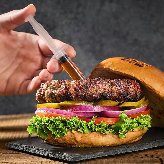 Hand injecting a flavor booster into a burger patty with a plastic syringe. Image by Megan Morello San Diego Food and Lifestyle Photographer.