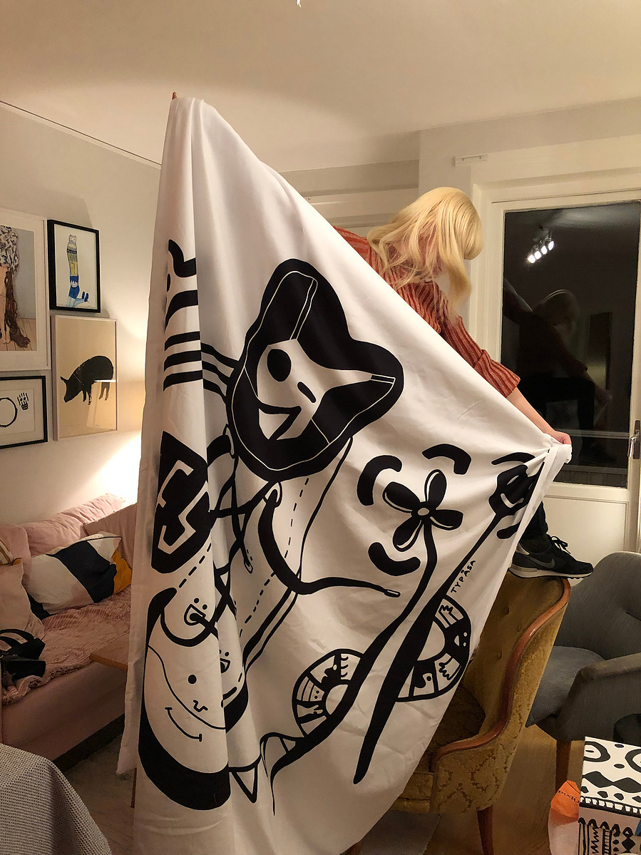 Woman holding an illustrated duvet cover in an artsy living room.