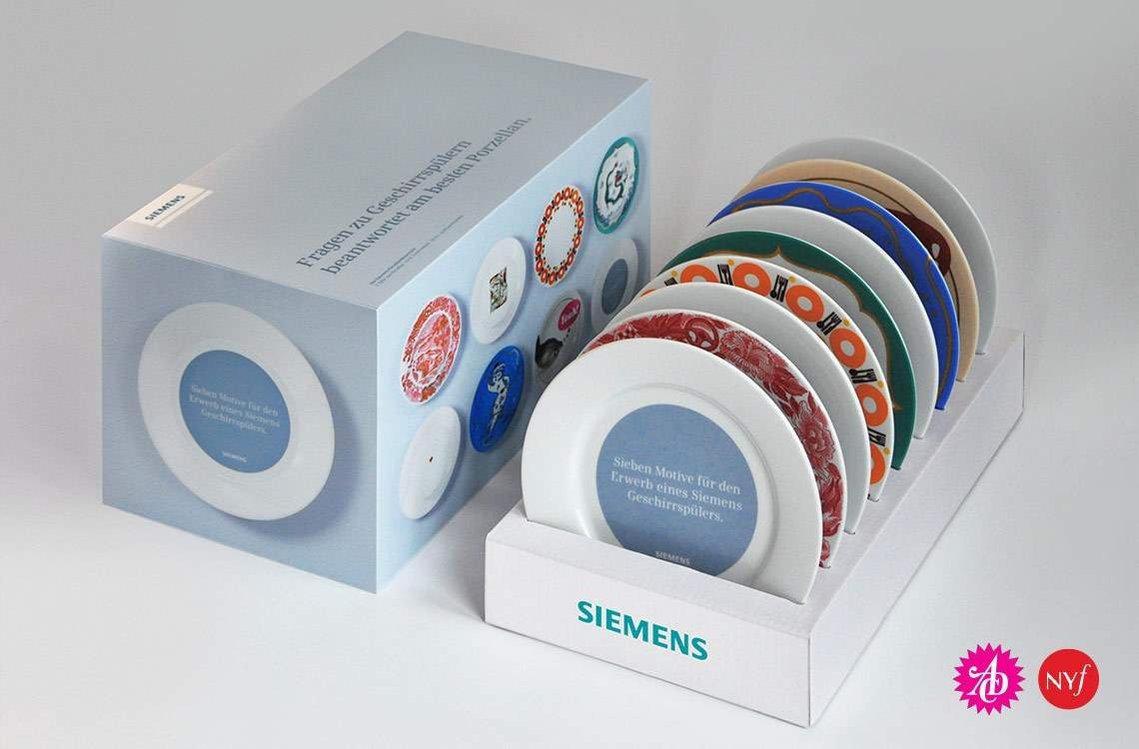 Eine rechteckige Verpackung, daneben mehrere bedruckte Teller in einem Papp-Tray, von Siemens