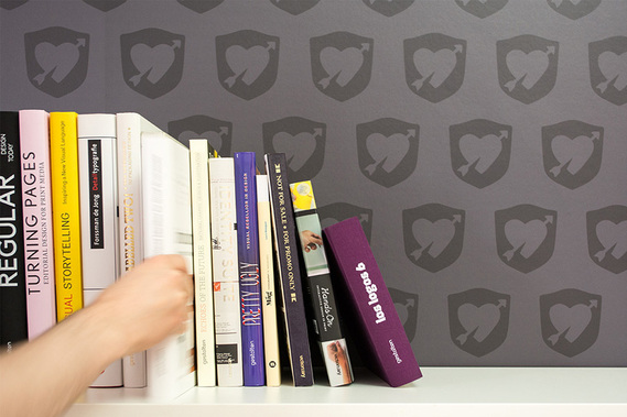 Eine Hand greift nach Büchern, im Hintergrund eine dunkelgraue Tapete mit dem GROSSE LIEBE Logo