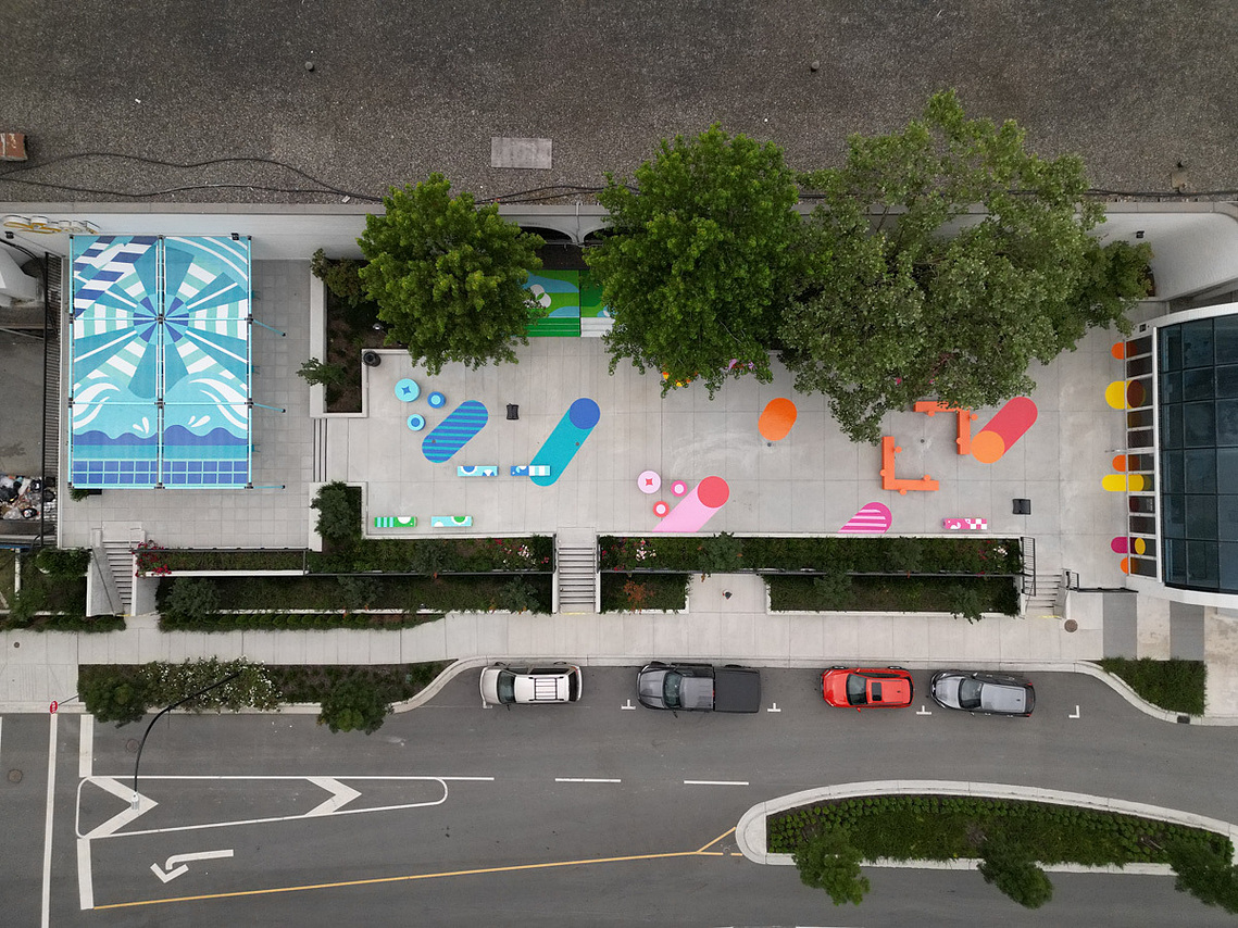 An aerial view of a patio vinyl installation featuring vibrant geometric designs outside of a shopping mall.