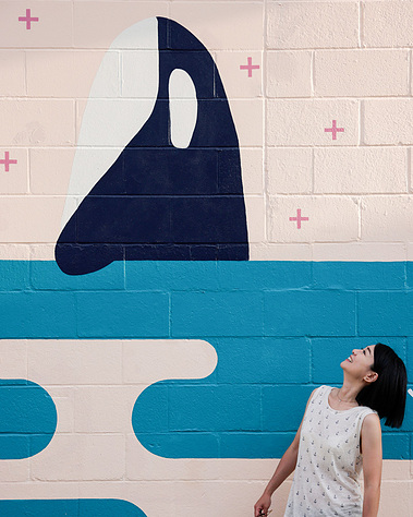 A photo of Annie Chen and the orca whale in her mural Sea to Sky.