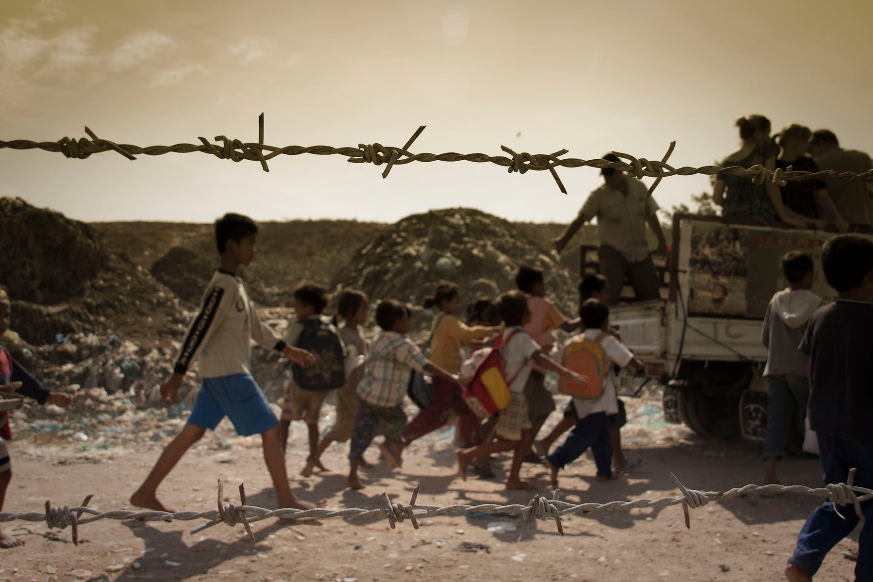 Article 20: "For a child whose own best interests cannot be allowed to remain in that environment, shall be entitled to special protection and assistance." Child gabage pickers follow an aid truck trough Stung Meanchey Dumpsite where they live, Cambodia.