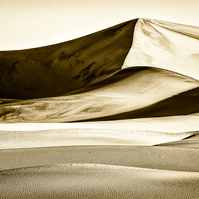 A warm-toned black and white image of a Death Valley sand dune highlighting the dune's contours, shape, texture, shadows, and fine details.