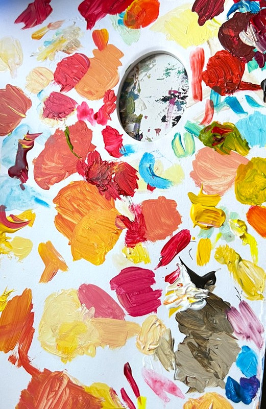 Detail of an artist's palette in yellows, oranges and light blues.