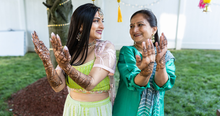 Mom and daughter pose showing mehndi and henna on their hands 