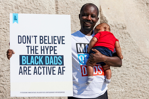 A marcher, who brought his newborn, shows off the signage .. Don’t believe the hype; Black dads are active AF.