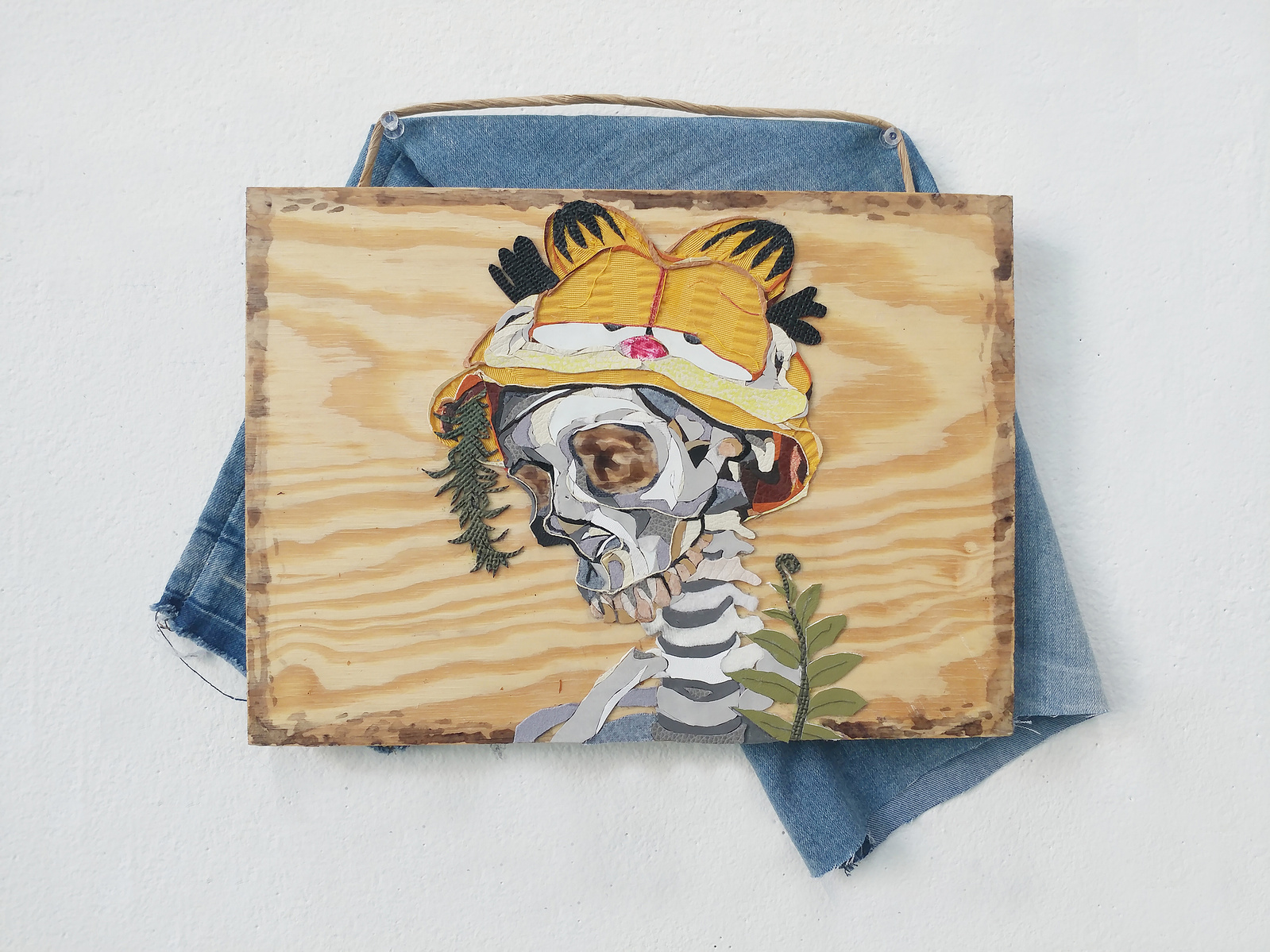 skeleton wearing a garfield hat fabric collage on wood panel