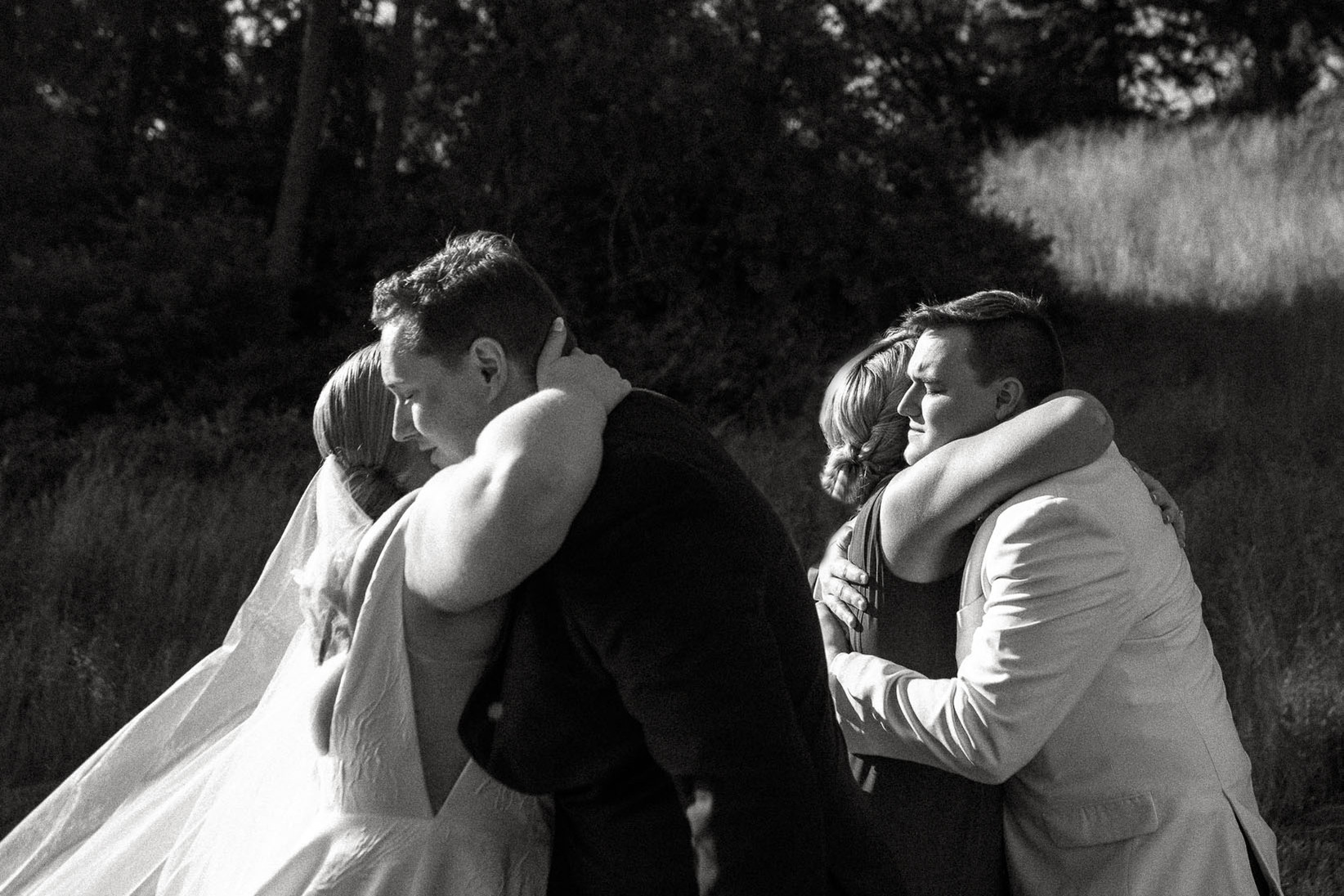 A bride and groom simultaneously hug their friends at their Barn at Castle Hill wedding in Ipswich MA