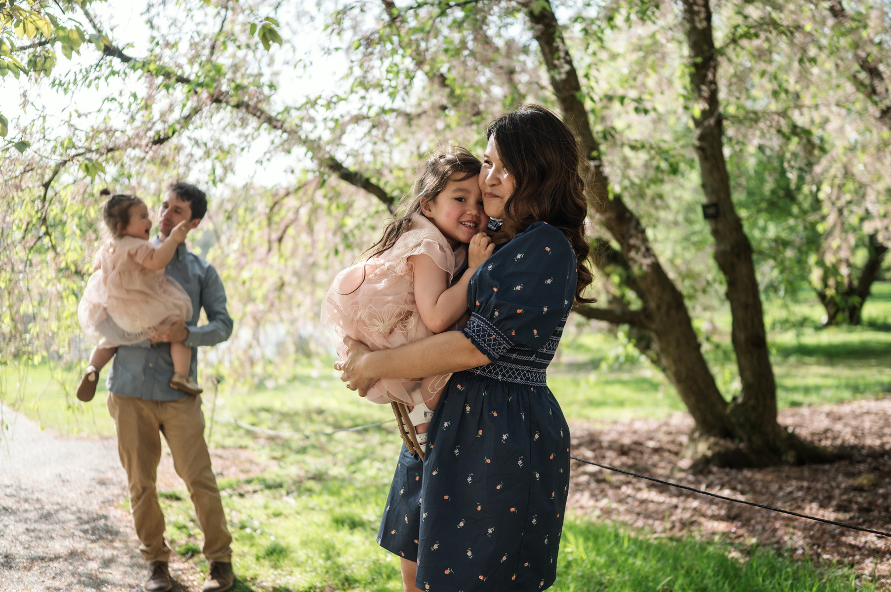 A family plays during their family photo session in Boston's Arnold Arboretum in spring.  Photo by West Roxbury family photographer Korri Leigh Photography