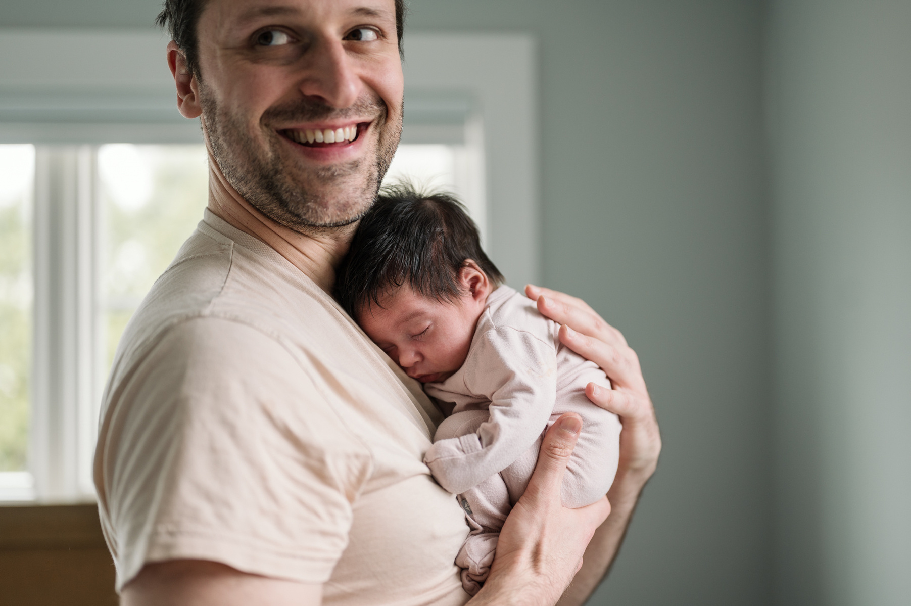 Dad smiles while holding his daughter  during an arlington newborn photography session
