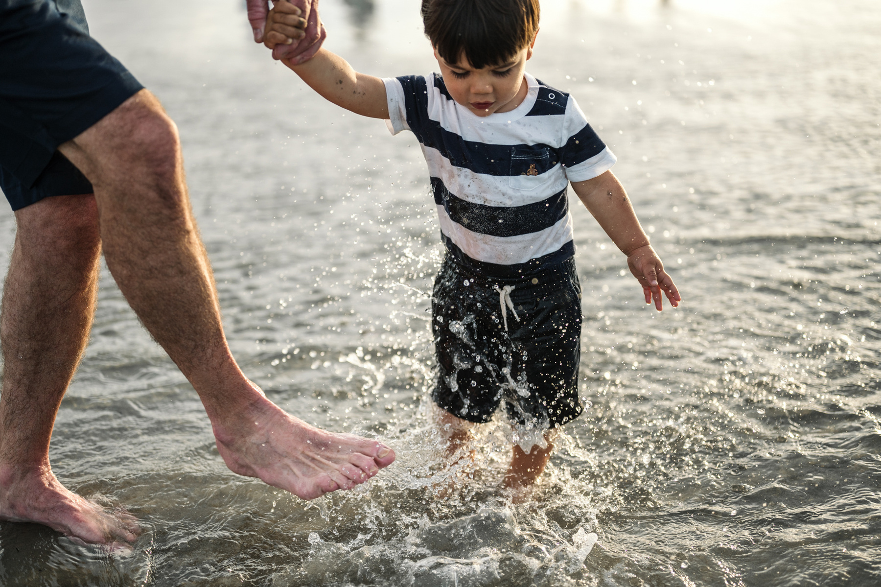 A toddler splashes in the ocean during their summer vacation photography session at Nantasket Beach by Boston family photographer Korri Leigh Crowley