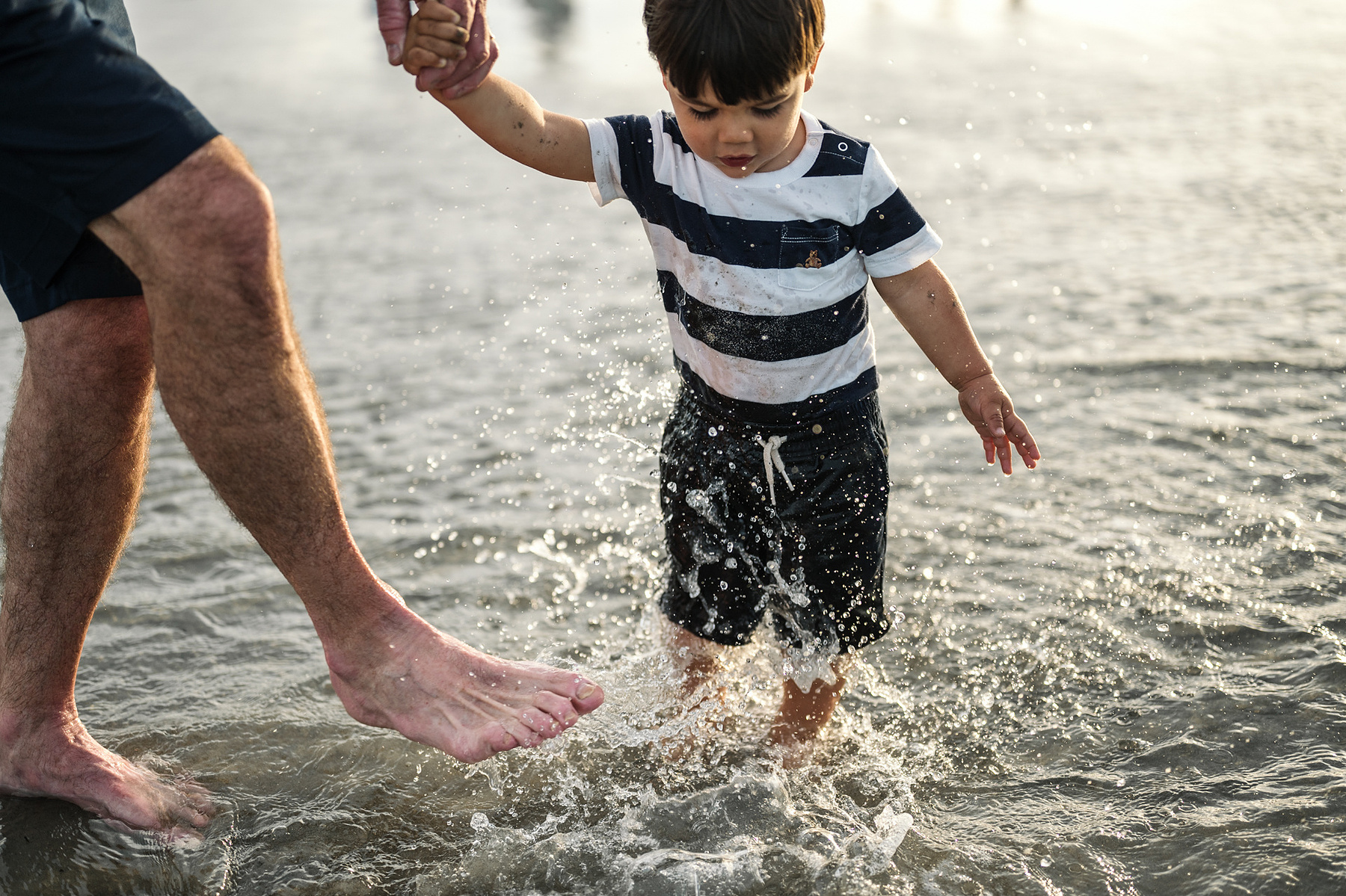A toddler splashes in the ocean during their summer vacation photography session at Nantasket Beach by Boston family photographer Korri Leigh Crowley