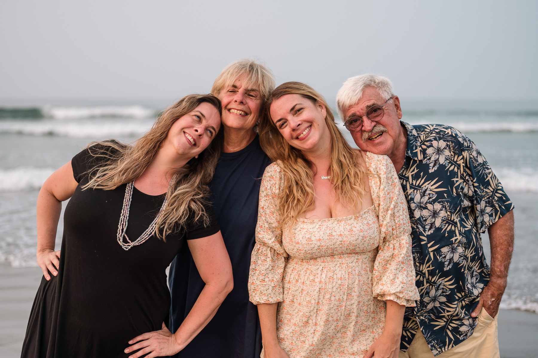 A family stands comfortably and smiles on Nantasket Beach at their Hull family photography session by Korri Leigh Photography