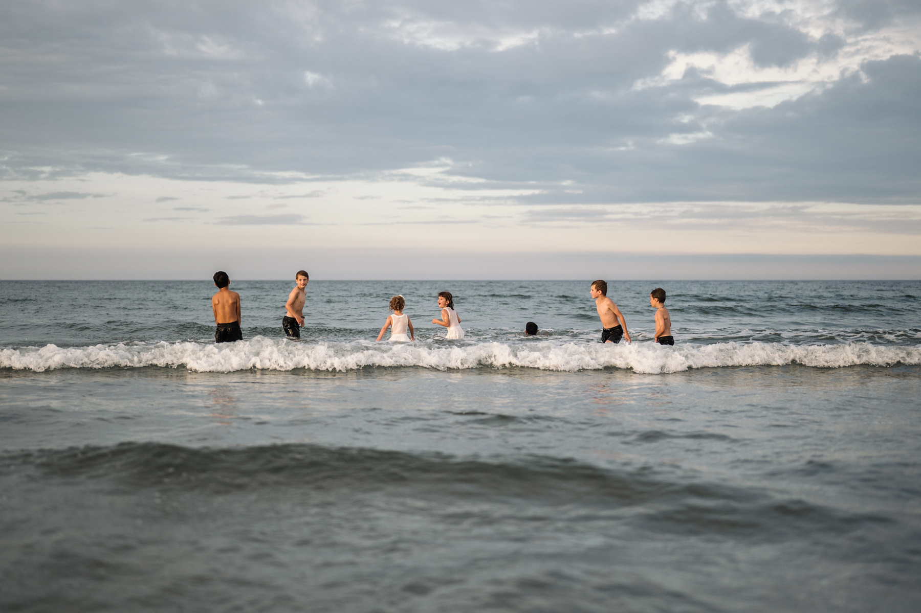 Children play in the water at sunset during their summer vacation photography session at Nantasket Beach by Boston family photographer Korri Leigh Crowley