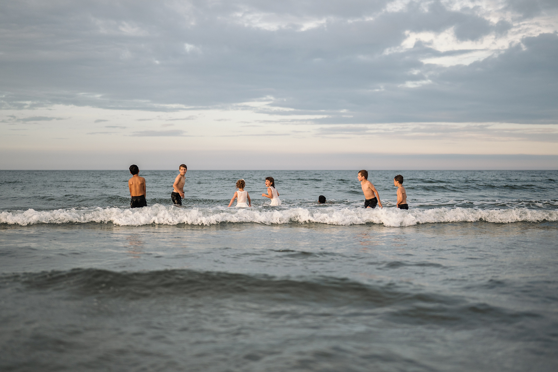 Children play in the water at sunset during their summer vacation photography session at Nantasket Beach by Boston family photographer Korri Leigh Crowley