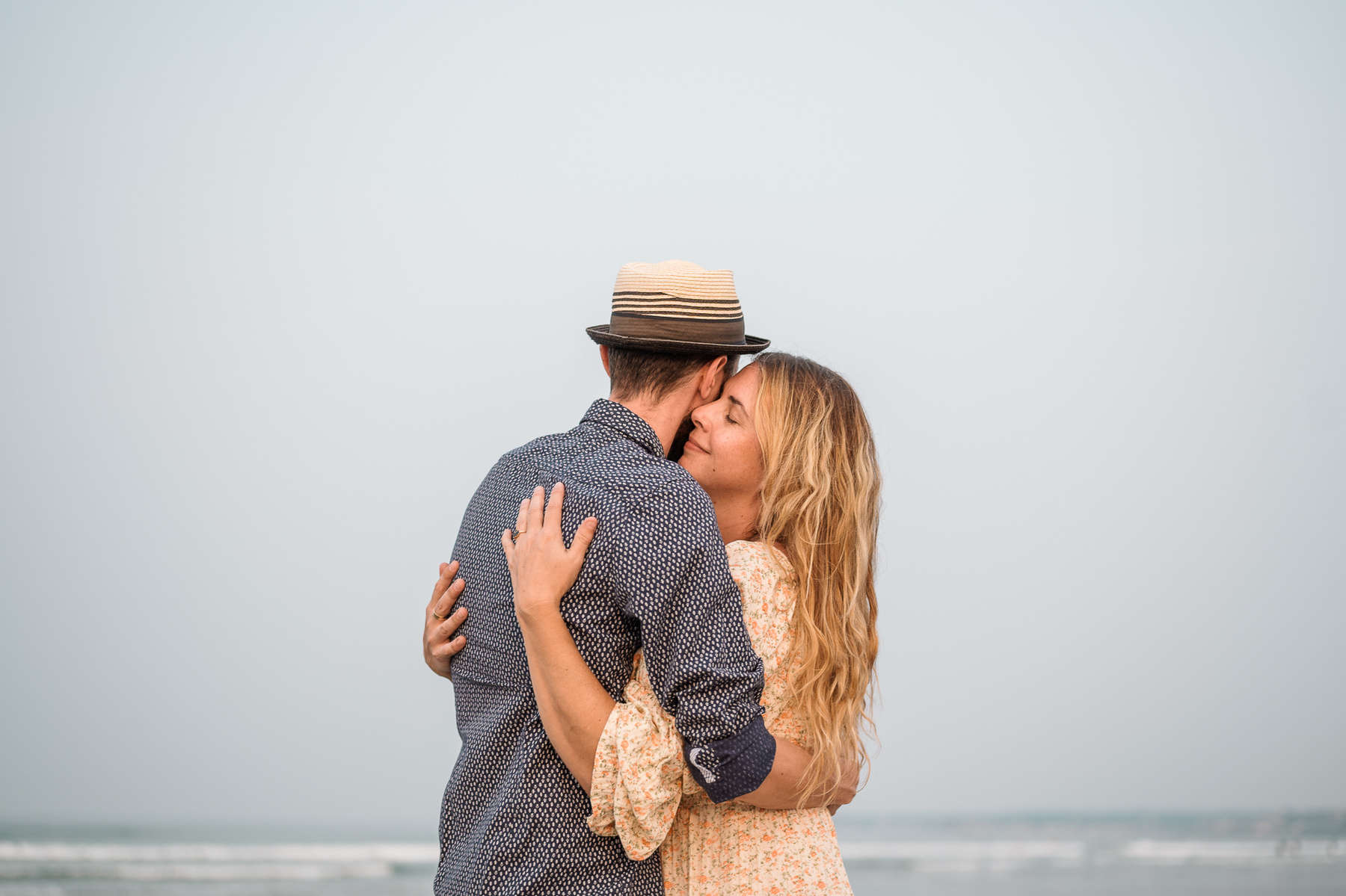 A couple hugs in front of the sky at their nantasket beach engagement session by Korri Leigh Photography