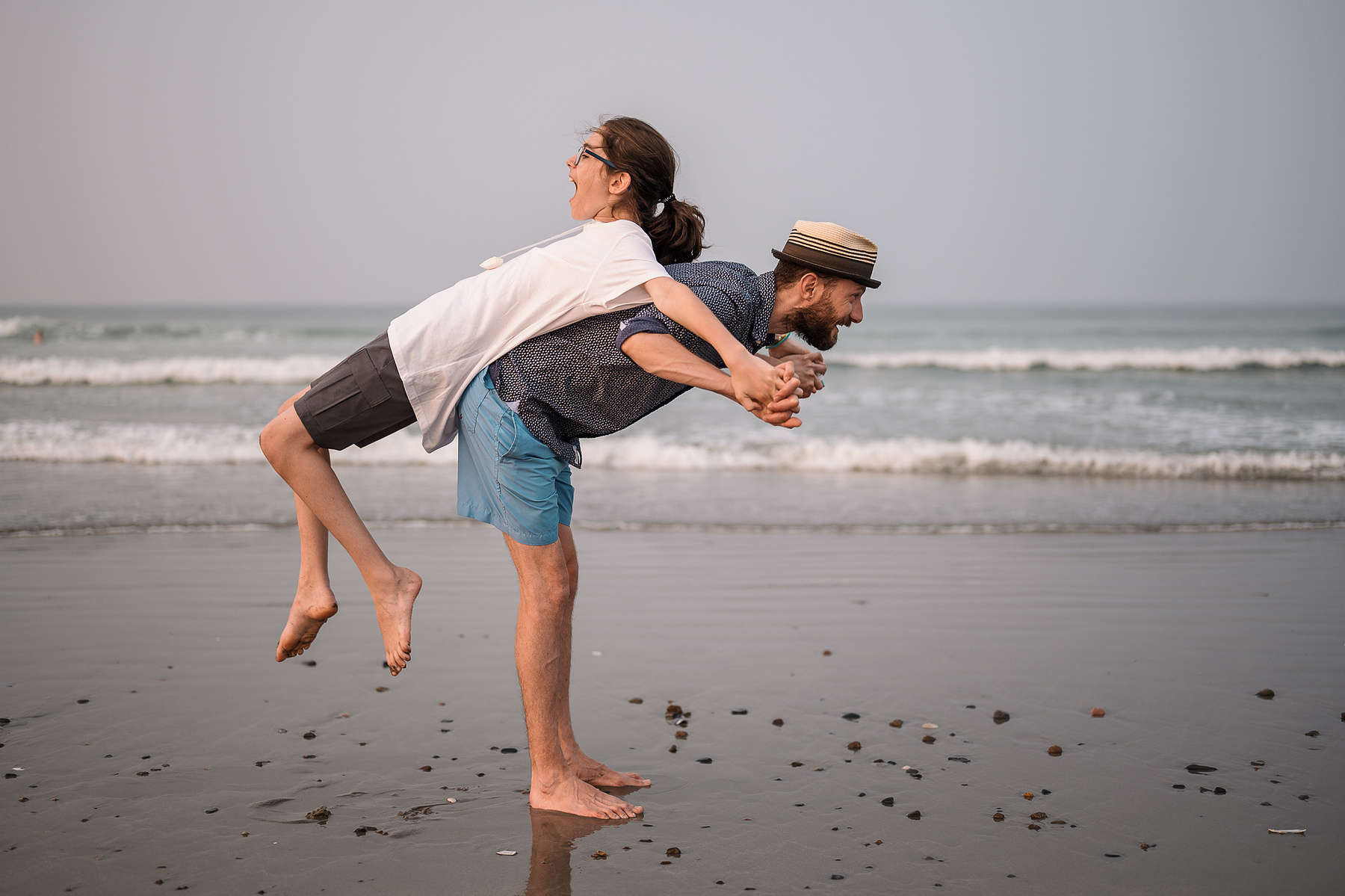 A father pulls his son onto his back on Nantasket Beach at their Hull family photography session by Korri Leigh Photography
