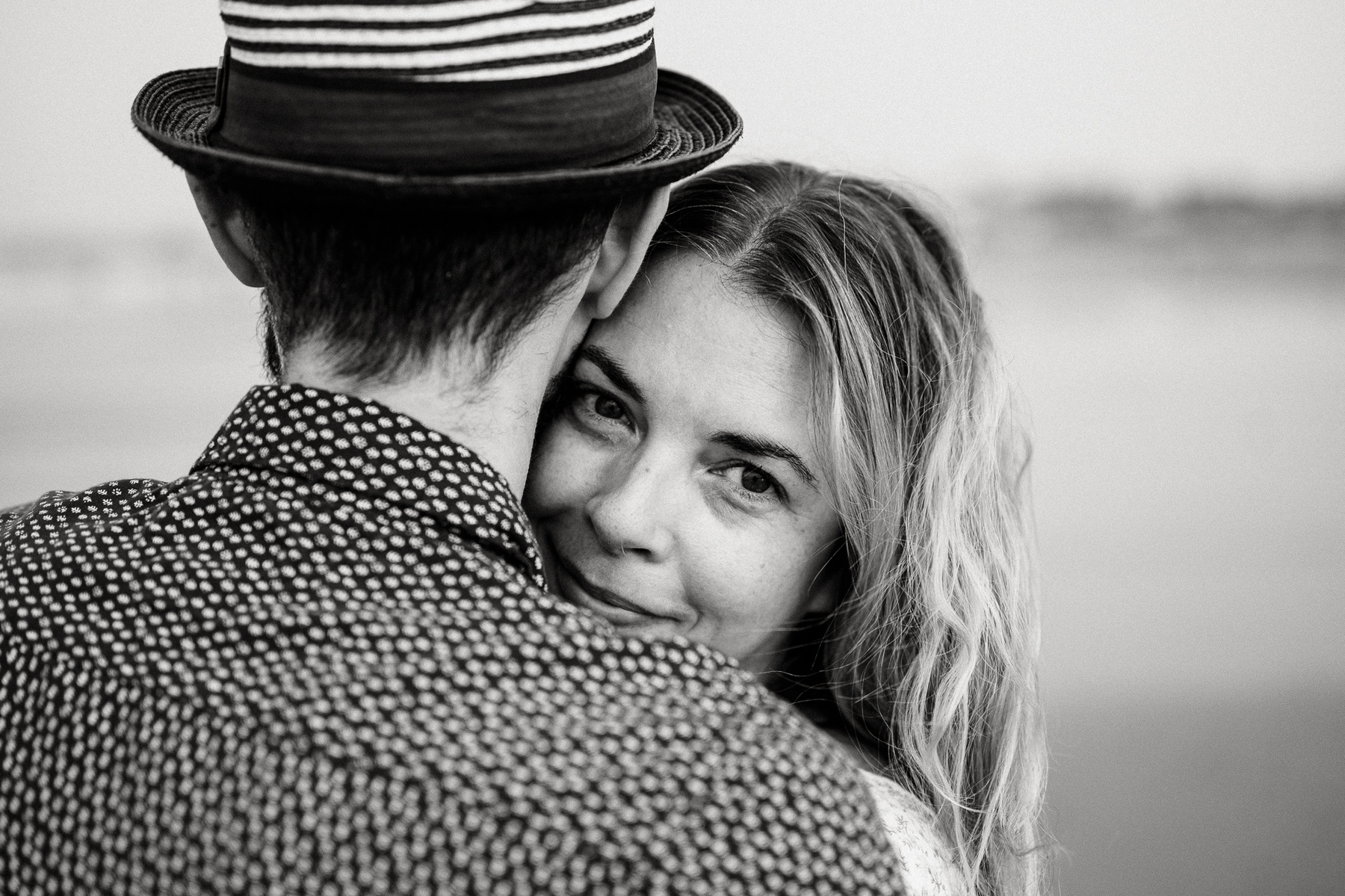 A woman peeks over her fiance's shoulder during their nantasket beach engagement session by Korri Leigh Photography