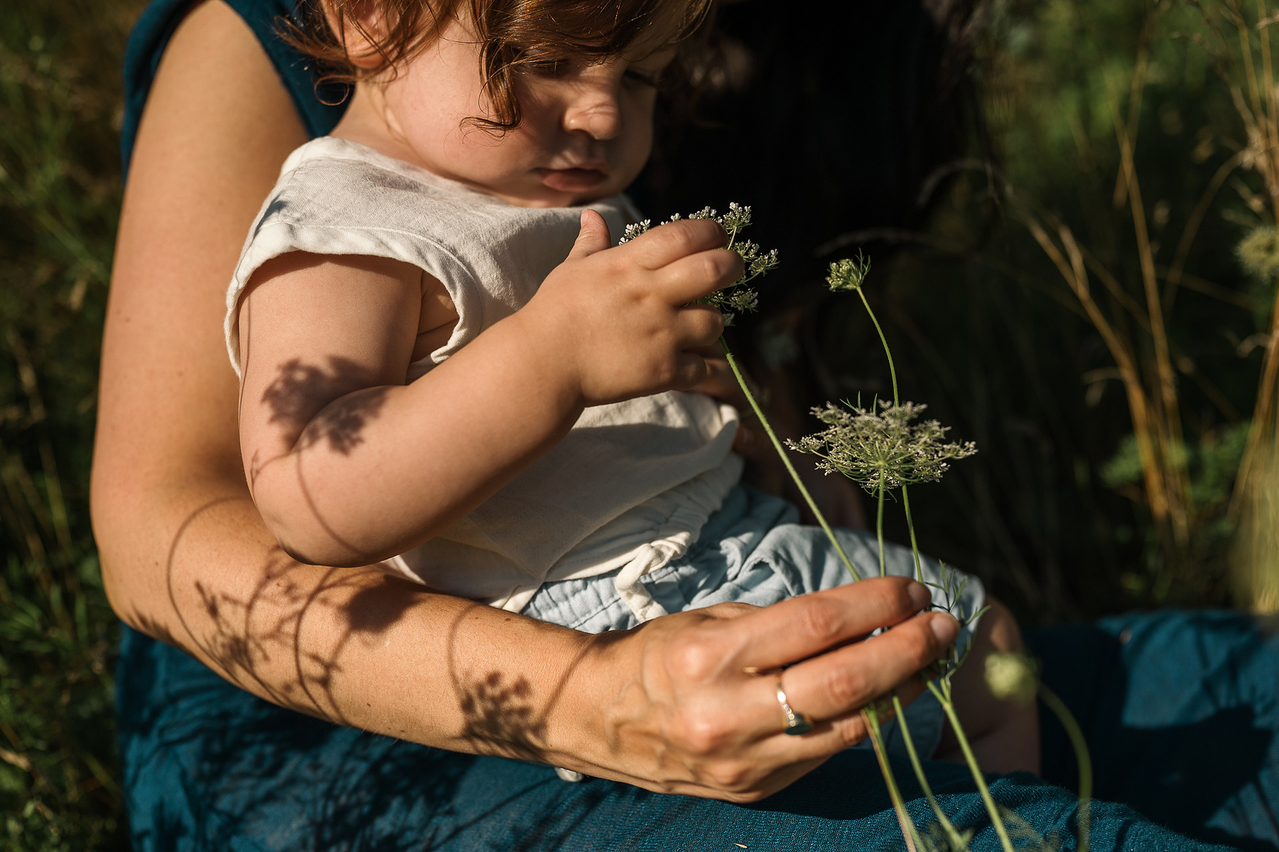 A mother and baby son in the flowers during their Brookline Family Photography session at Fisher Hill Reservoir Park in Brookline MA