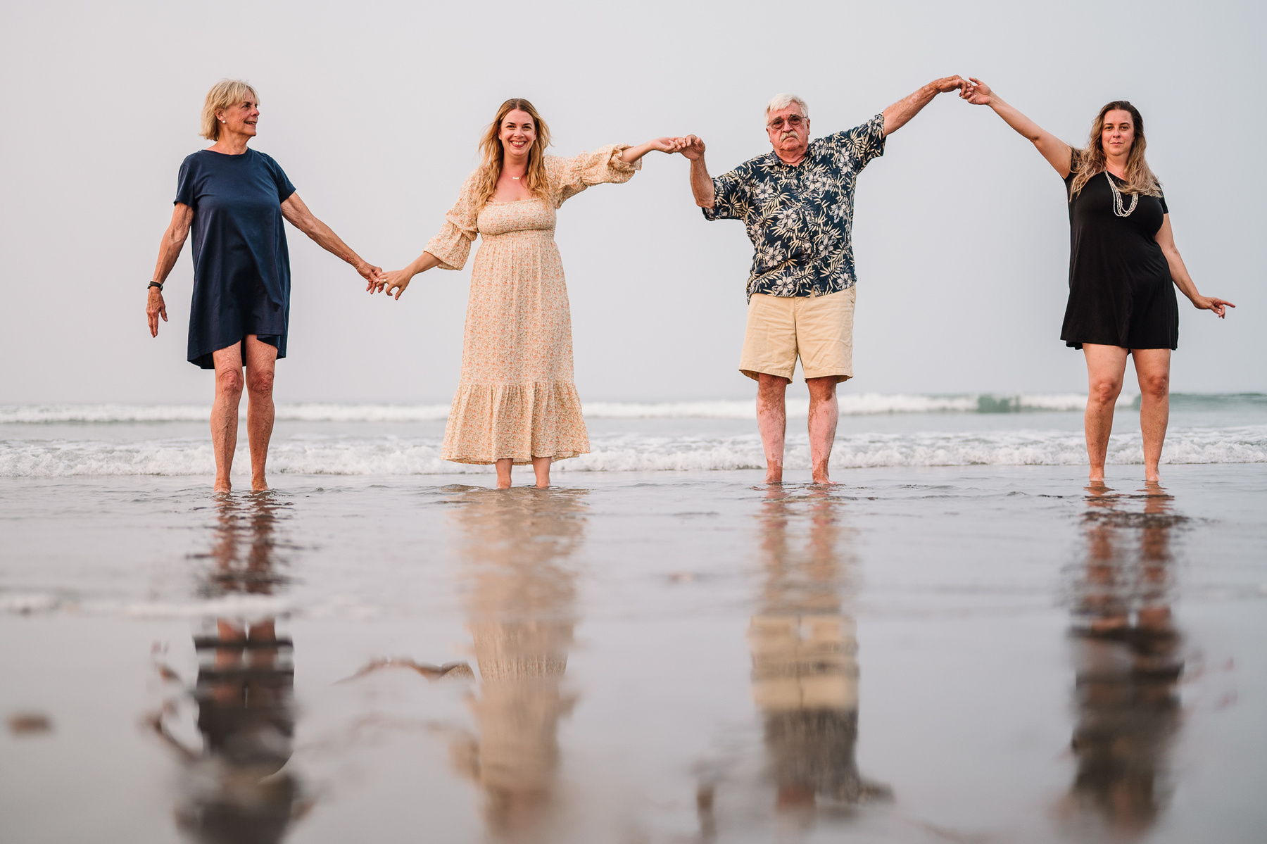 A family stands in a line and holds hands on Nantasket Beach at their Hull family photography session by Korri Leigh Photography