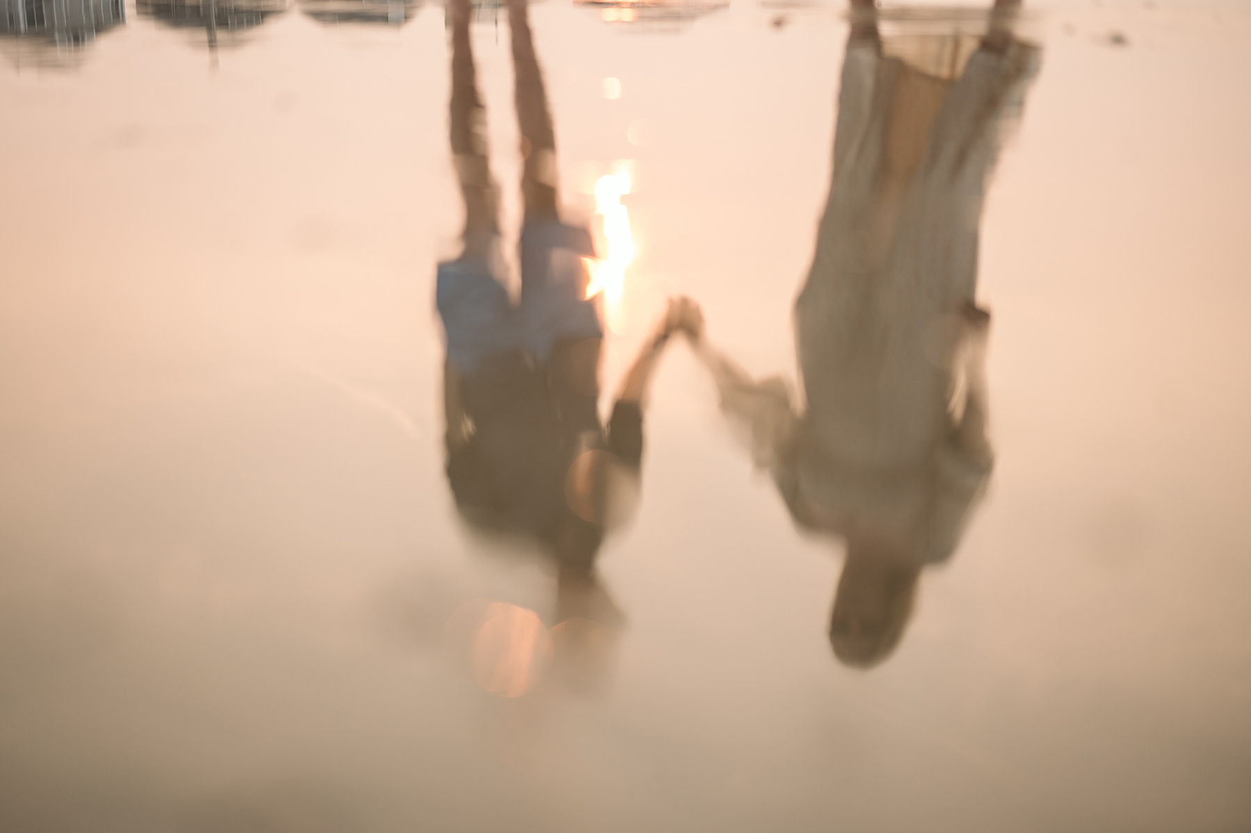 The reflection in the sand of a couple holding hands at their nantasket beach engagement session by Korri Leigh Photography