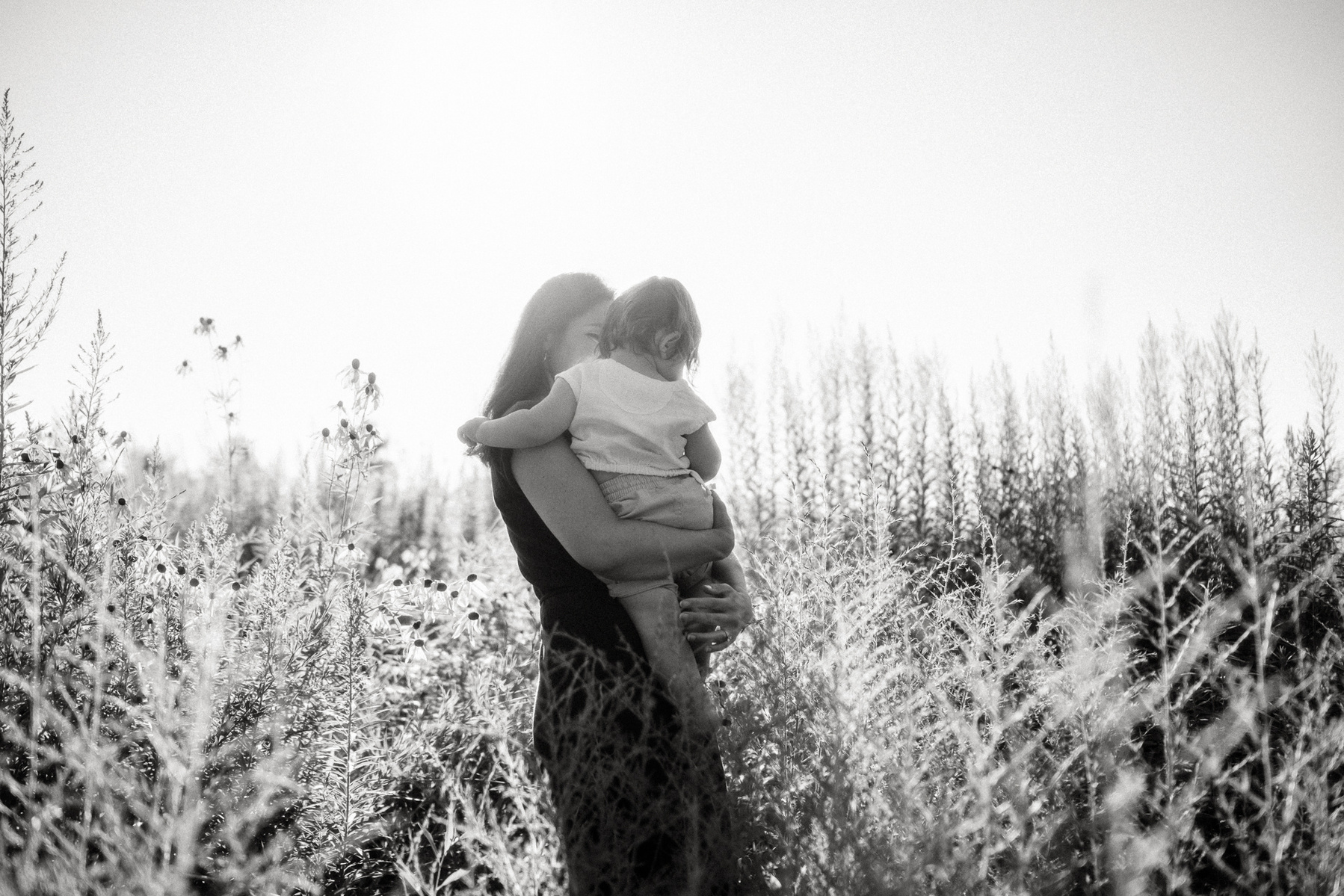 A mother hugs her child in a sunny field at Fisher Hill Reservoir Park in Brookline MA