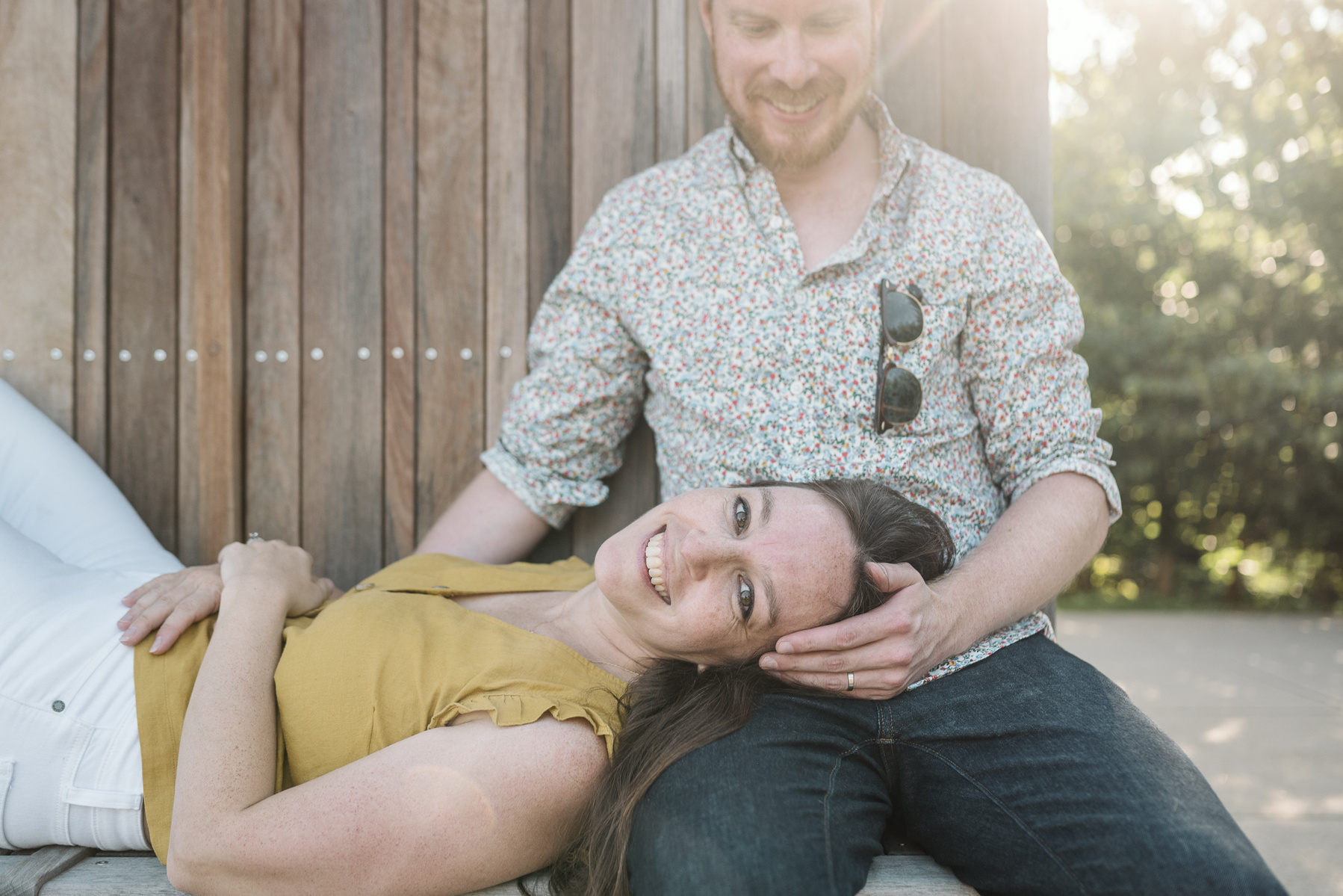 A Mom lays her head in her husband's lap during a family photo session at Fisher Hill Reservoir Park in Chestnut Hill by Brookline family photographer Korri Leigh Photography