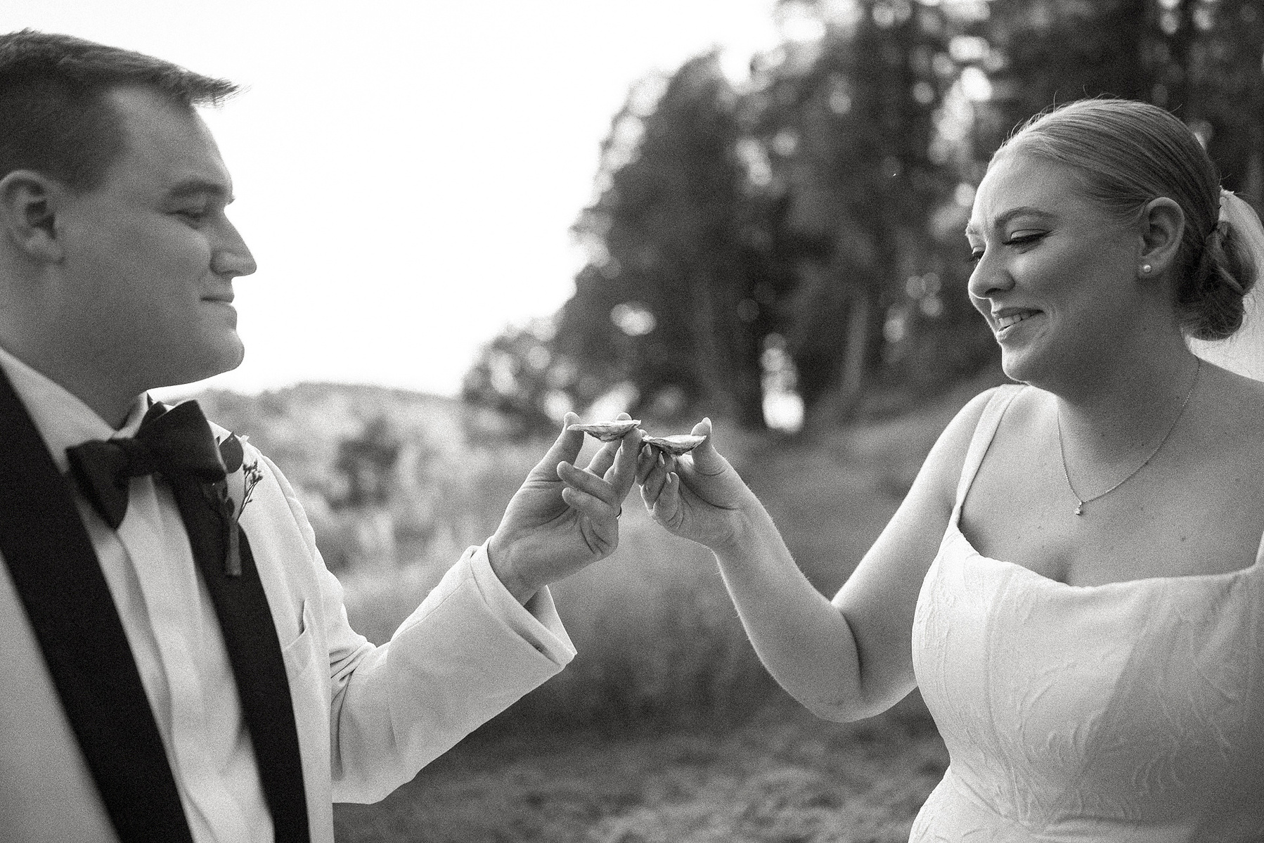 A bride and groom hold up oysters before eating them at their Crane Estate wedding