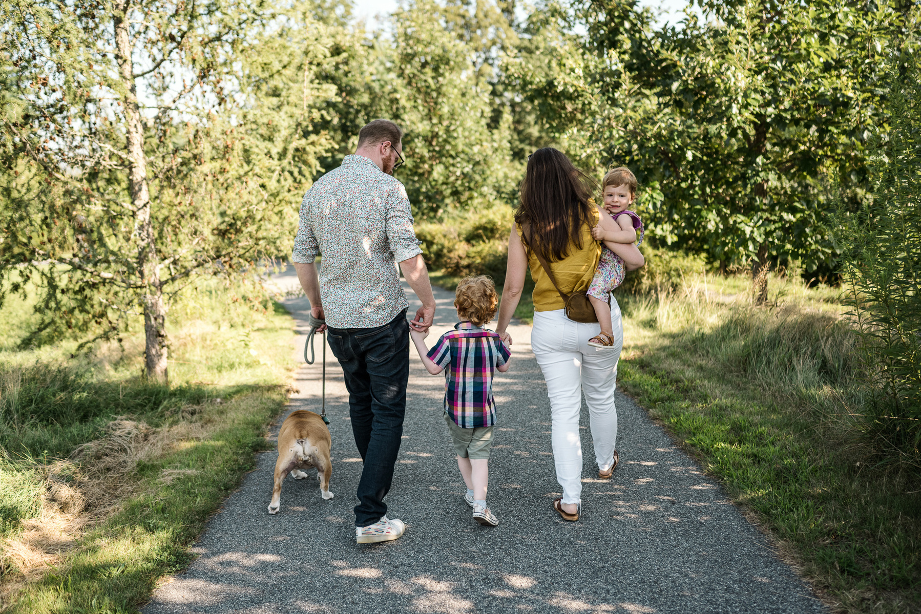 A family walks on a path at Fisher Hill Reservoir Park in Chestnut Hill by Brookline family photographer Korri Leigh Photography