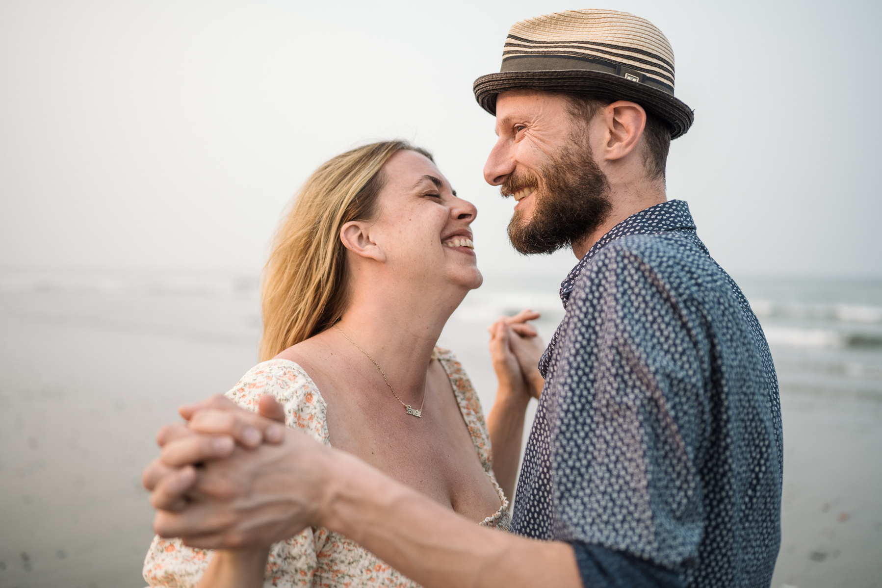 A couple smiles at each other in front of the ocean at their nantasket beach engagement session by Korri Leigh Photography