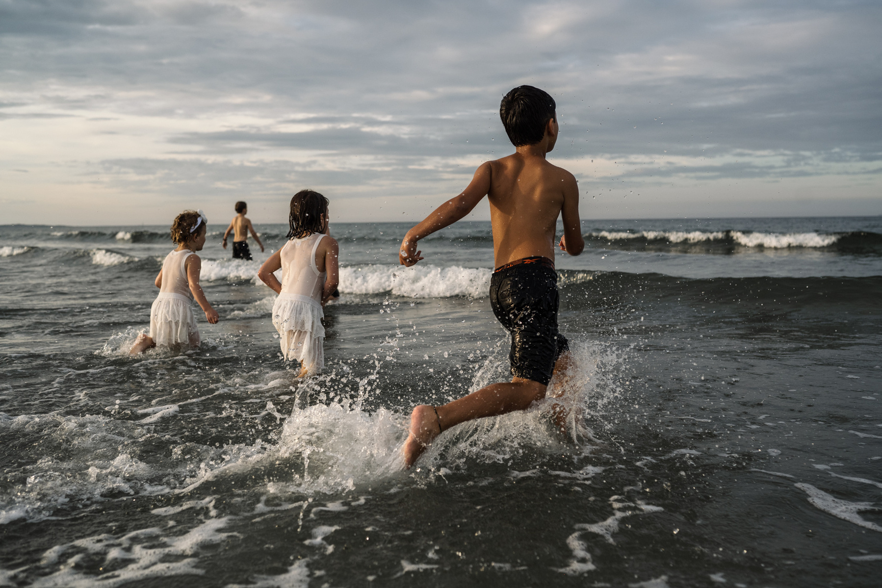 Children run into the ocean during their summer vacation photography session at Nantasket Beach by Boston family photographer Korri Leigh Crowley