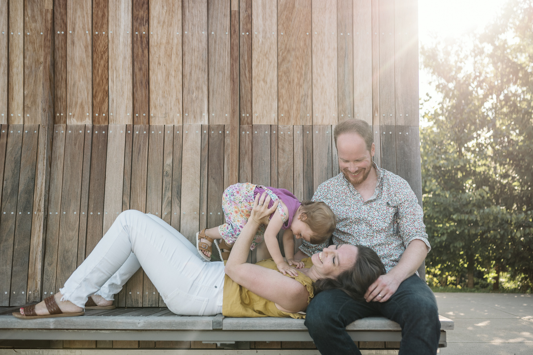 A Mom lays her head in her husband's lap during a family photo session at Fisher Hill Reservoir Park in Chestnut Hill by Brookline family photographer Korri Leigh Photography