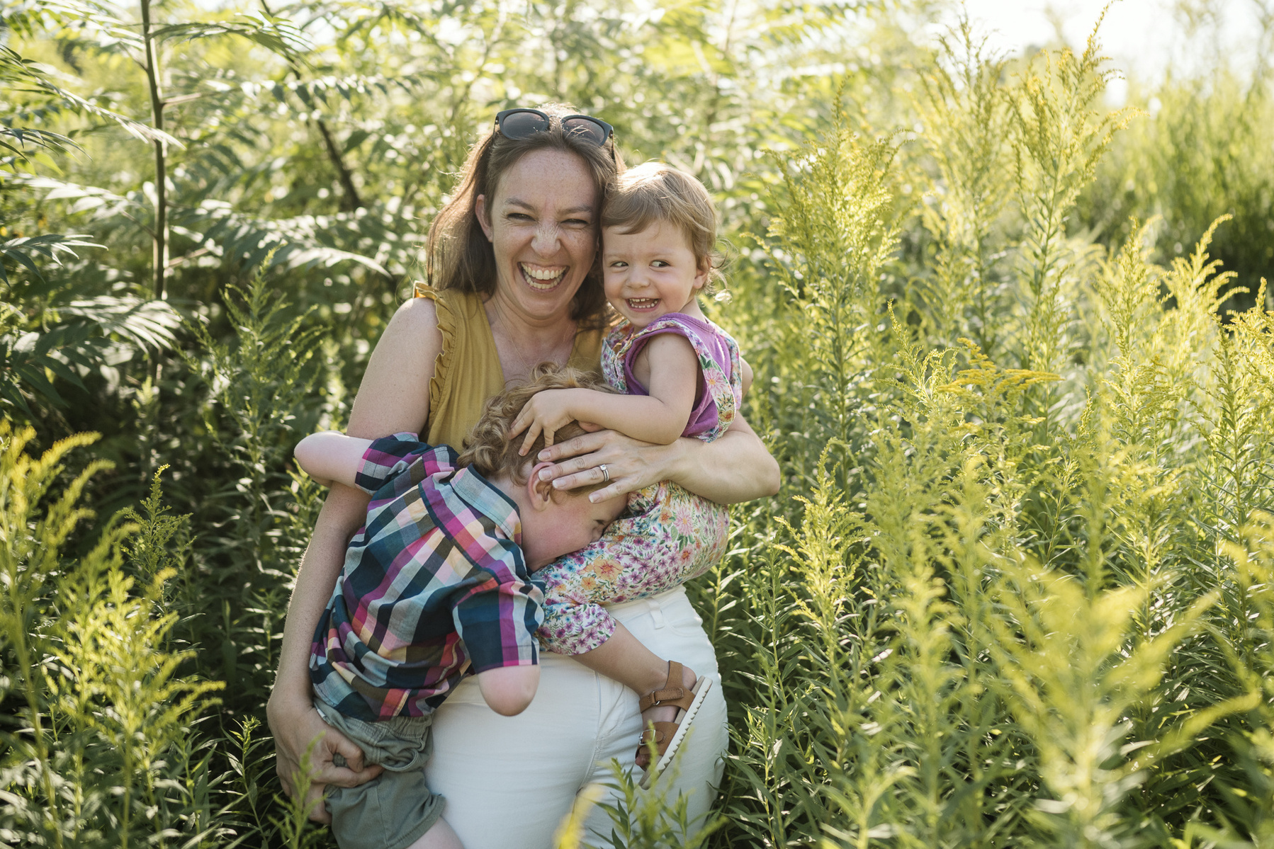 A Mom laughs while holding her children at Fisher Hill Reservoir Park in Chestnut Hill by Brookline family photographer Korri Leigh Photography