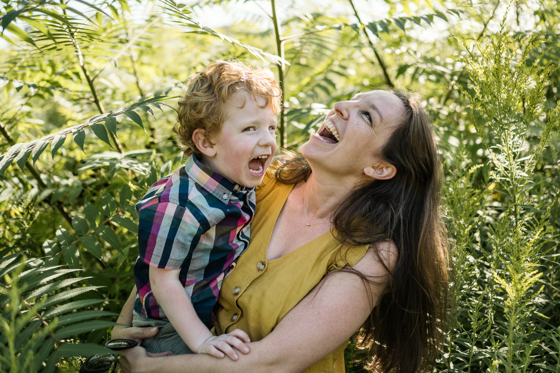 A Mom laughs while holding her children at Fisher Hill Reservoir Park in Chestnut Hill by Brookline family photographer Korri Leigh Photography