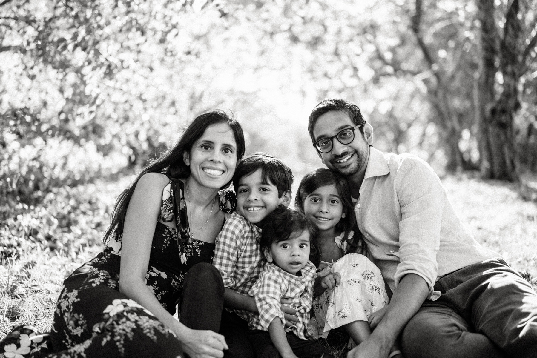 A family snuggles in the sunshine in their arnold arboretum family photography session captured by jamaica plain family photographer korri leigh crowley