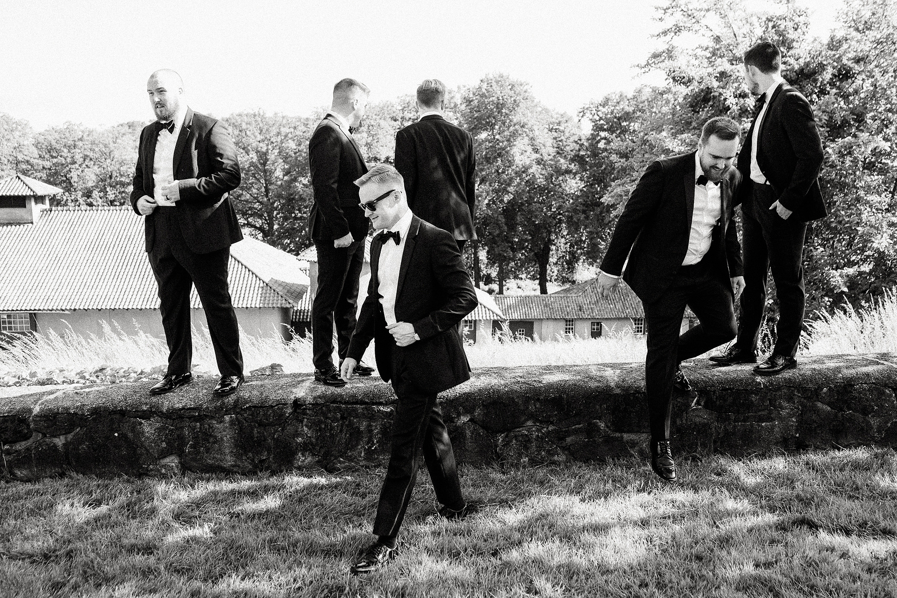 Men in tuxedos jump from a stone wall on the property of the Crane Estate in Ipswich MA
