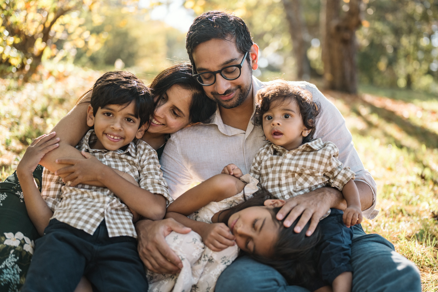 A family snuggles in the sunshine in their arnold arboretum family photography session captured by west roxbury family photographer korri leigh crowley