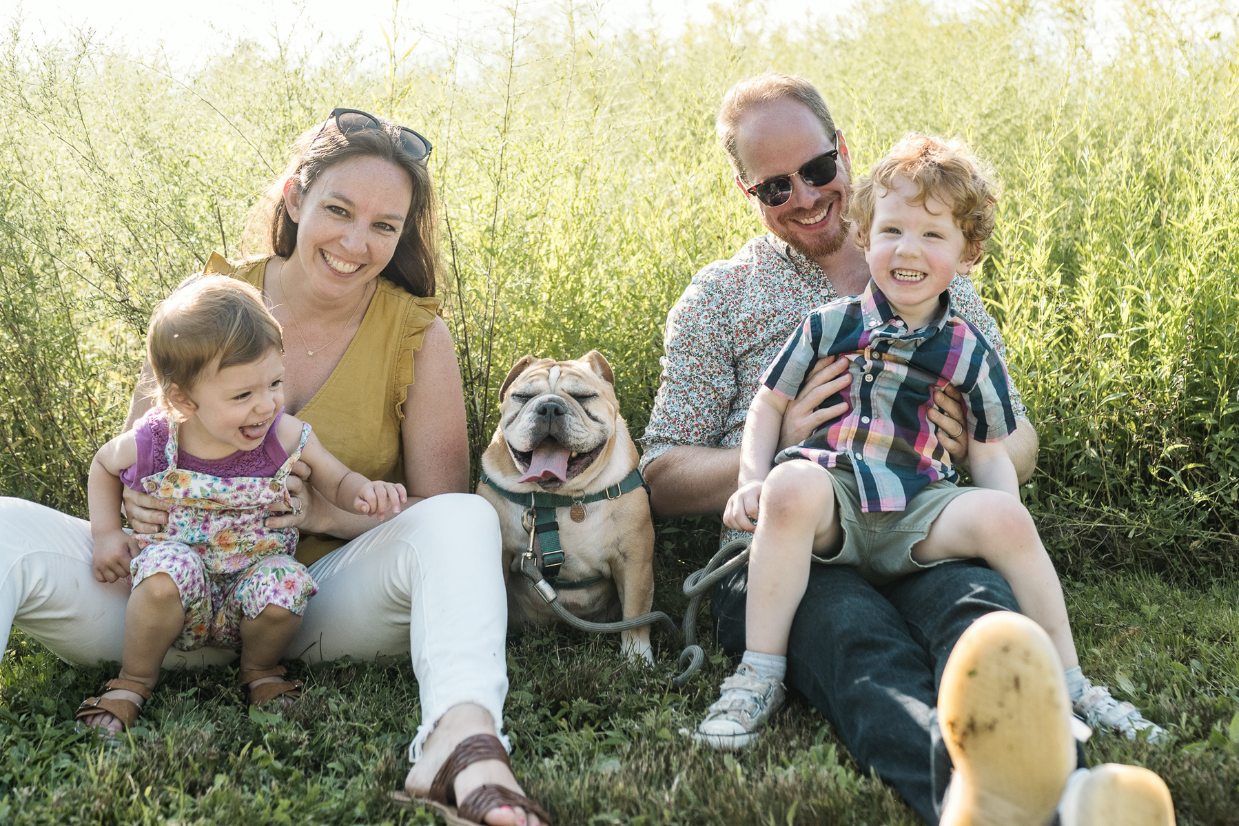A dog sits in the middle of a family photo session at Fisher Hill Reservoir Park in Chestnut Hill by Brookline family photographer Korri Leigh Photography
